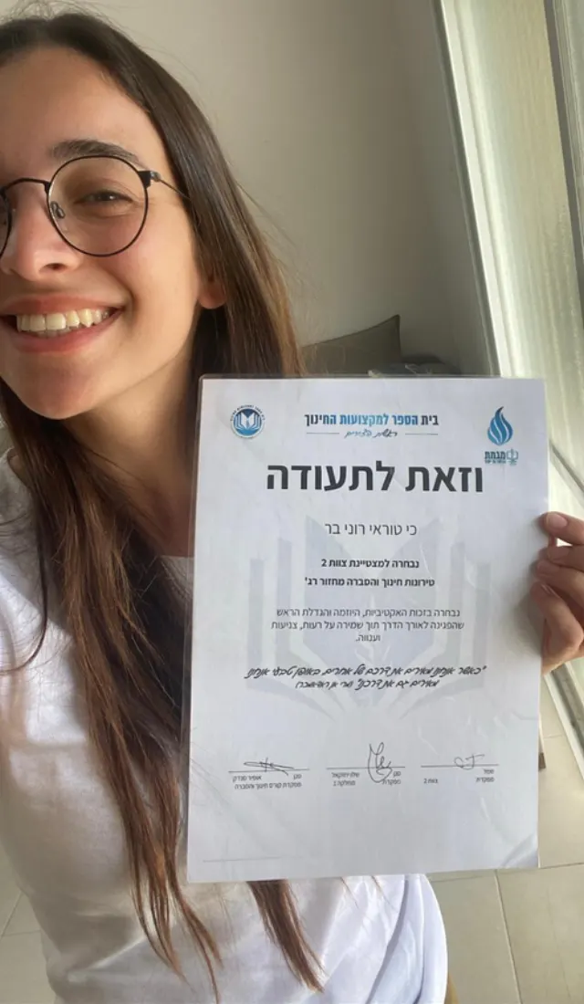 רוני בר מחזיקה תעודה ומחייכת